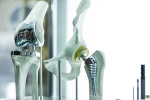 A medical model of a hip implant with a knee implant next to it.