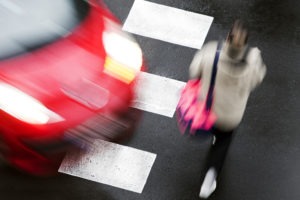 A speeding car is about to hit a pedestrian on a crosswalk.