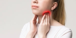 woman massaging enlarged lymph nodes on throat