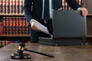 A lawyer with legal books and a gavel putting paperwork in a briefcas