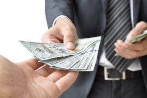 Man in a suit and tie handing money to the recipient