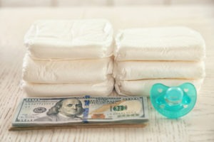 One-hundred-dollar bills stacked next to diapers and a pacifier