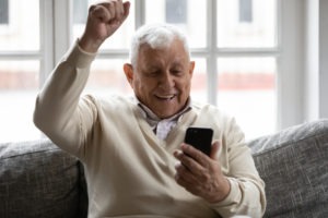 excited elderly man looking at phone