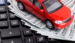 model car atop hundred-dollar bills and calculator