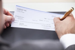 man signing a check made out to him