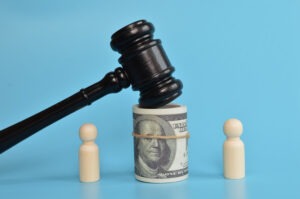 A wooden gavel on a white surface is surrounded by several U.S. hundred-dollar bills, hinting at the complex interplay of law and settlement loans.